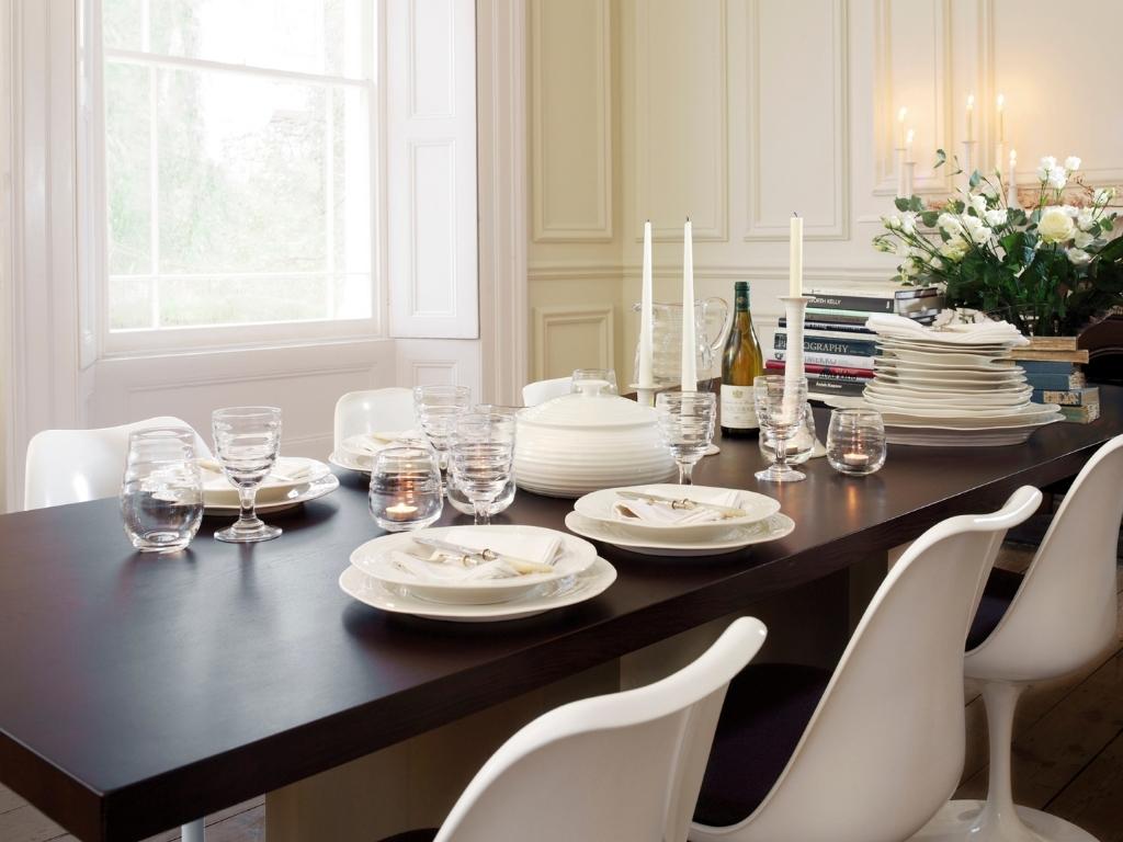 Beautiful dark would dining table with white dishware ready for a dinner party