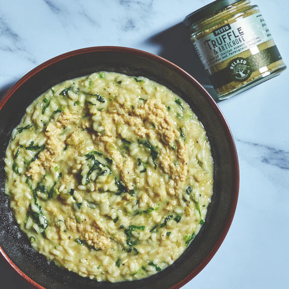 Photo of a bowl of Risotto and jar of pesto beside it